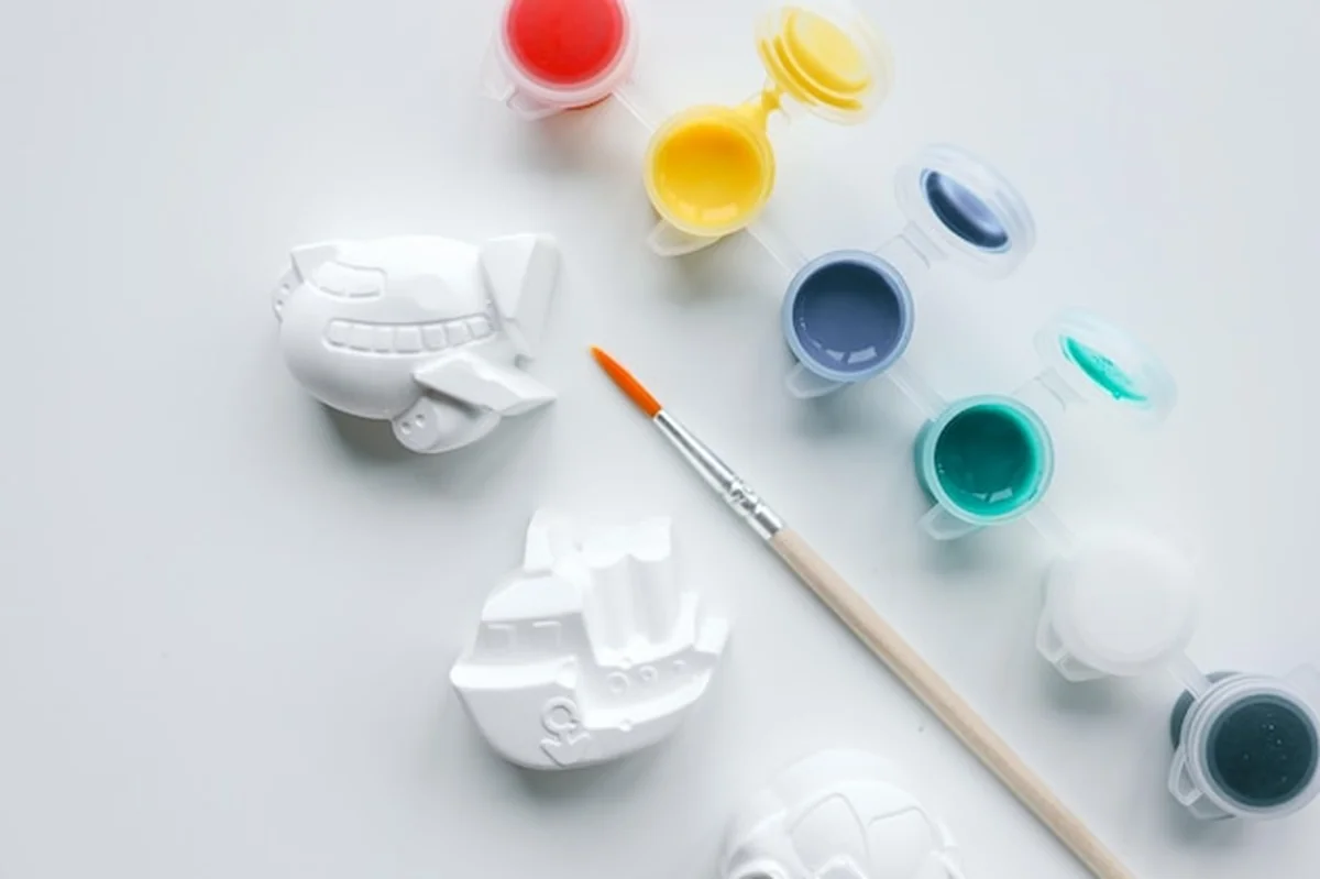 Dziecko maluje figurkę z gipsu jasnymi kolorami