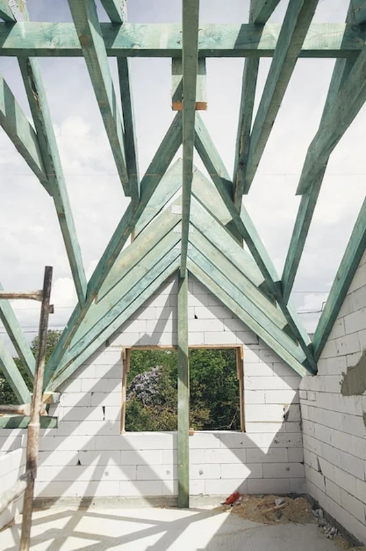 Niedokończone wiązary dachowe na poddaszu z krokwiami i belkami