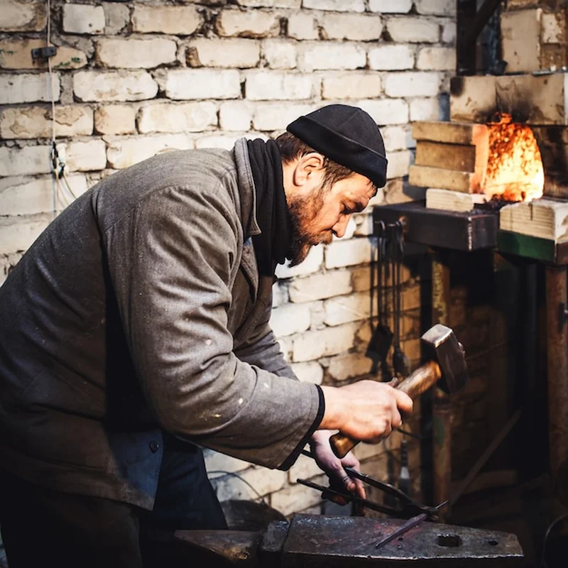 Kowal kuje gorący metal na kowadle