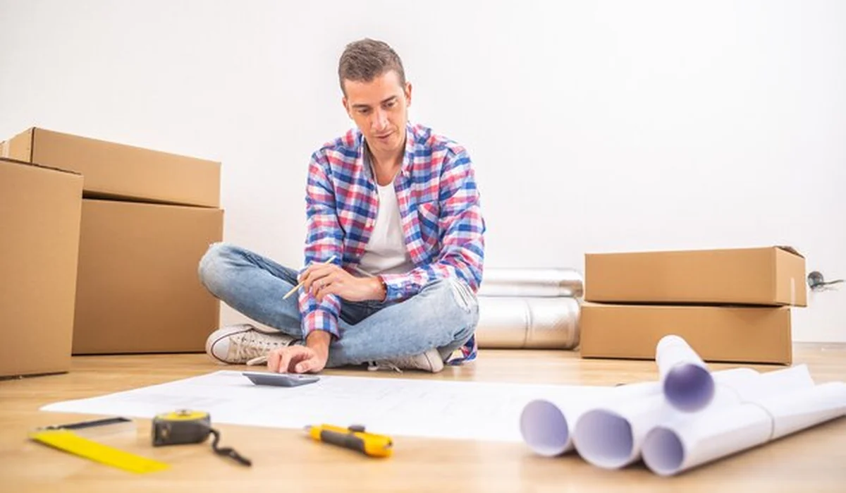 Mężczyzna siedzi na podłodze w nowym domu po przeprowadzce