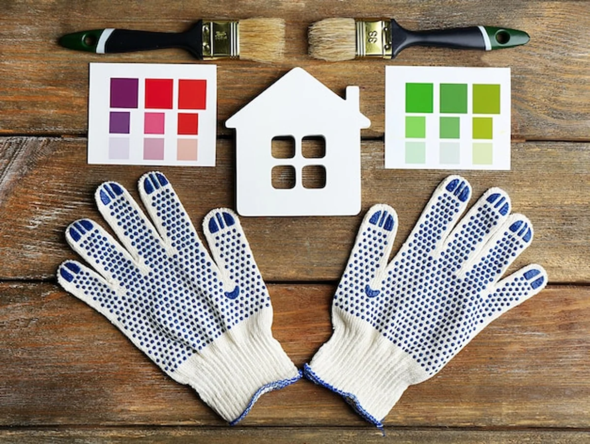 Próbki kolorów, rękawice i pędzle na drewnianym stole