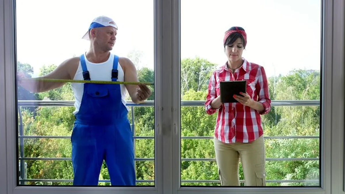 Robotnik i asystentka mierzą okna