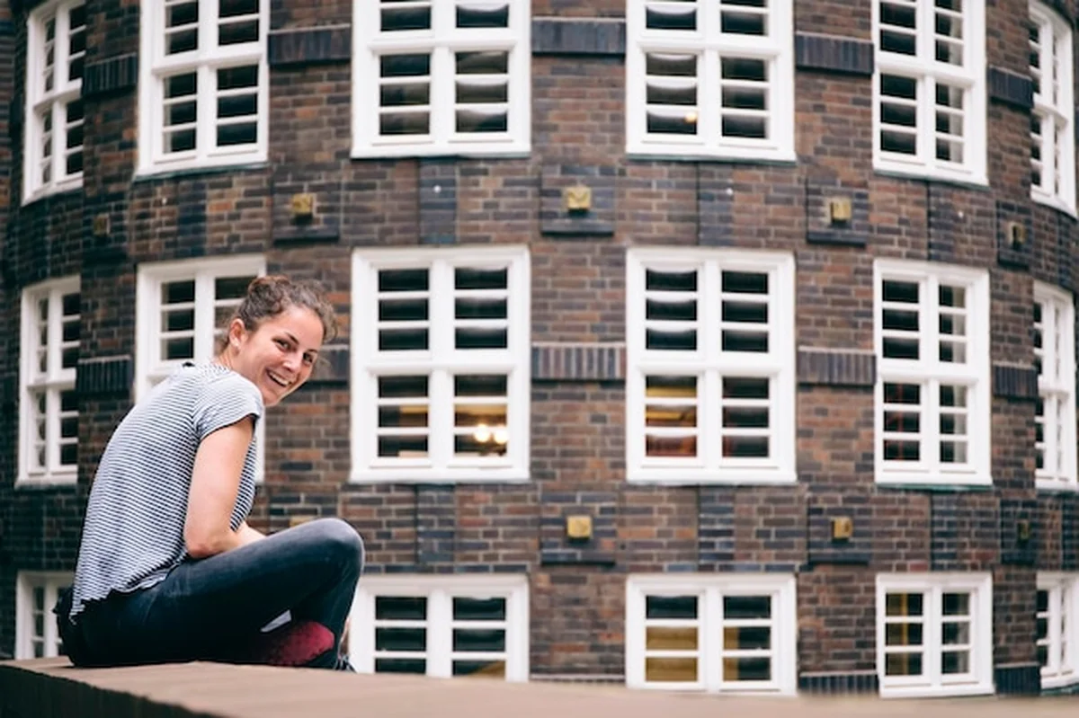 Młoda kobieta siedząca na ścianie przed budynkiem