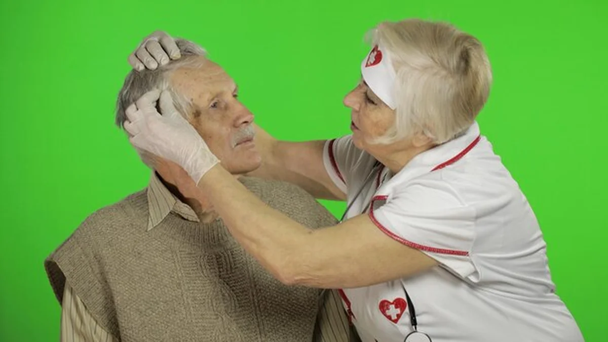 Dojrzała pielęgniarka bada starszego pacjenta