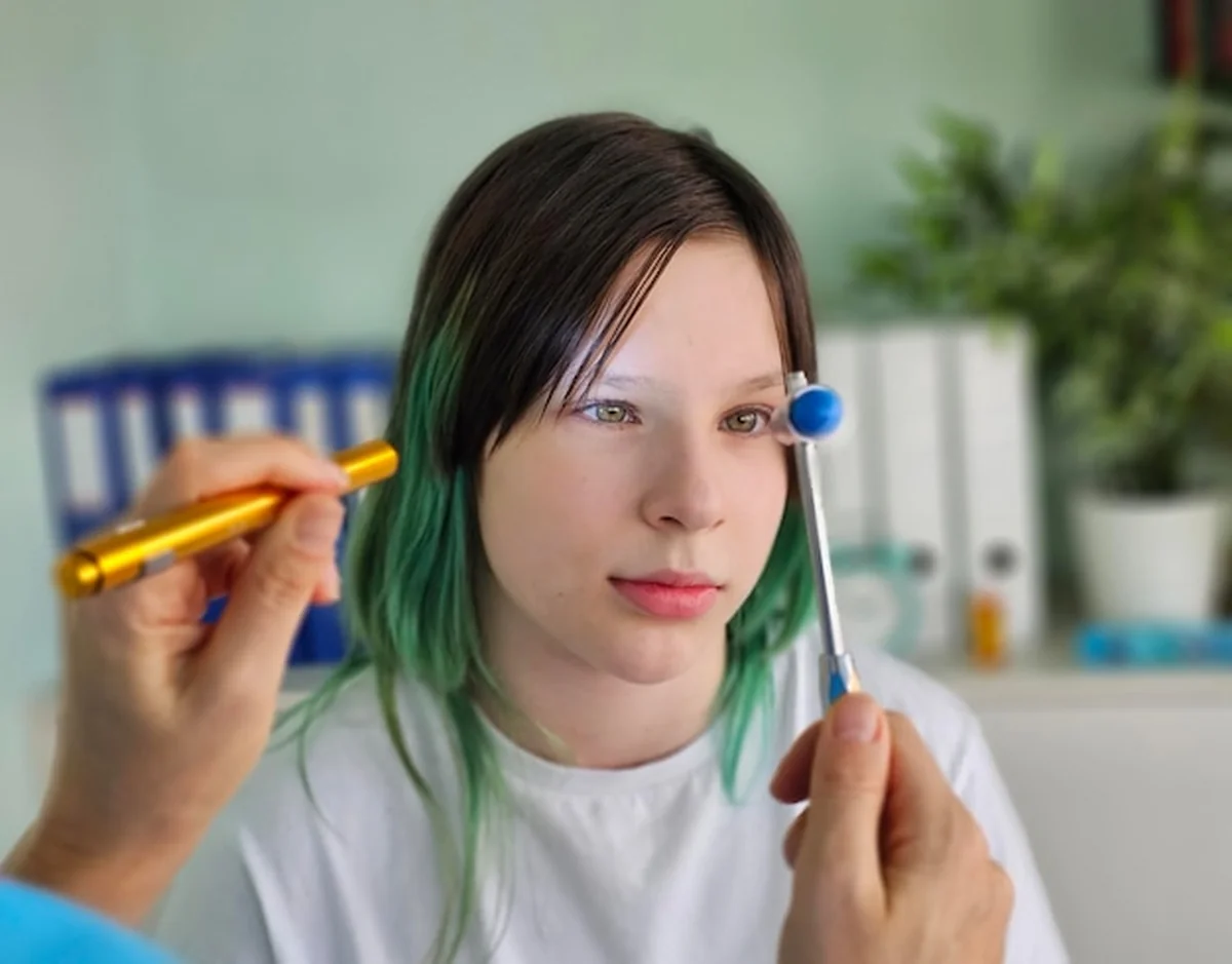 Neurolog sprawdza odruch wzrokowy nastolatki przy użyciu młotka neurologicznego