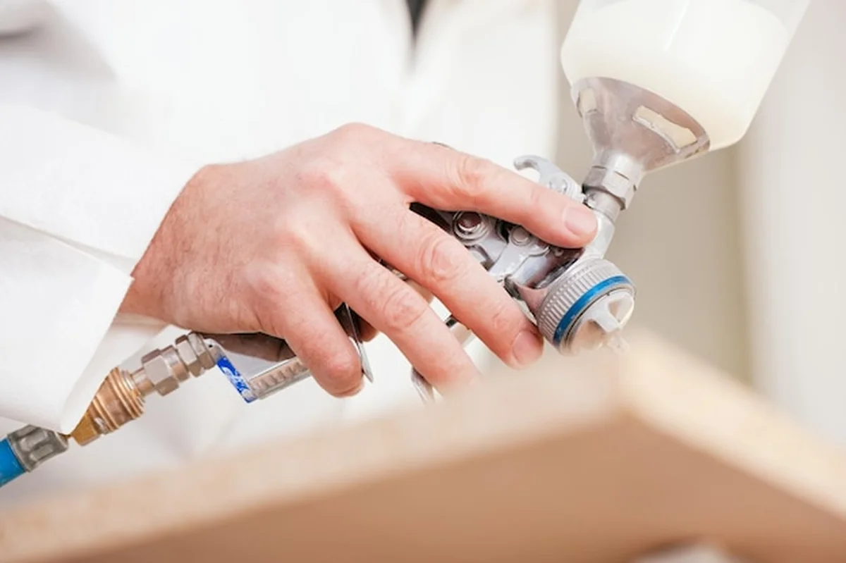 Stolarz maluje kawałek drewna w pokoju malarskim