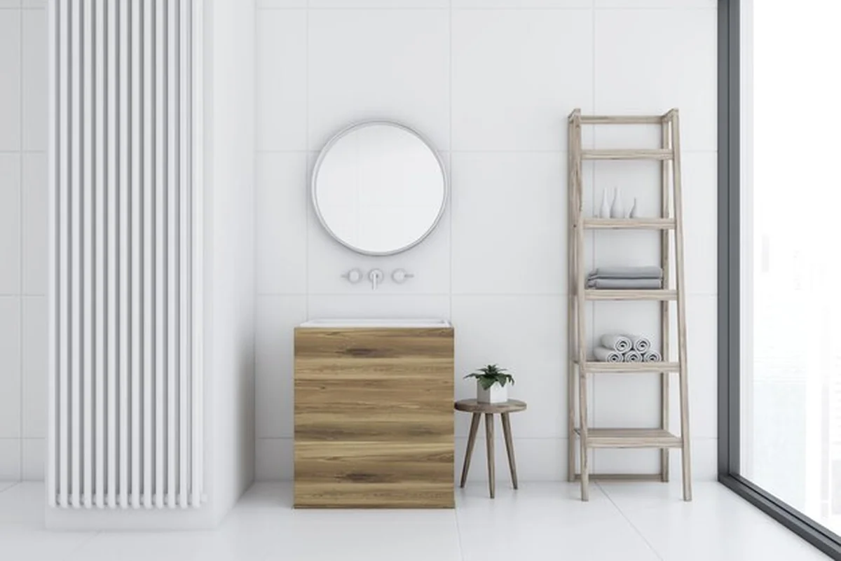 Łazienka z białymi kafelkami, drewnianym zlewem i okrągłym lustrem