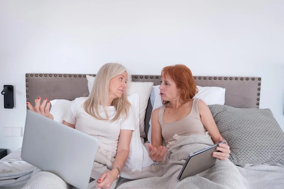 Starsza para lgtbi rozmawia w łóżku przed snem korzystając z tabletu