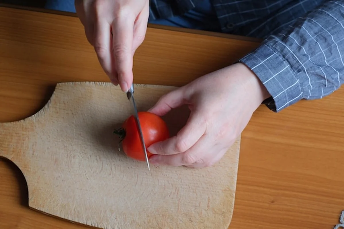 Starsza kobieta krojąca pomidora w kuchni