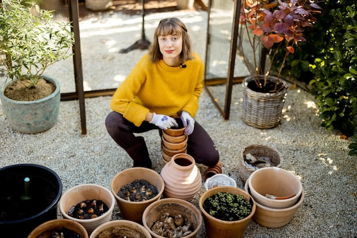 Kobieta sadzi kwiaty w dzbankach w ogrodzie