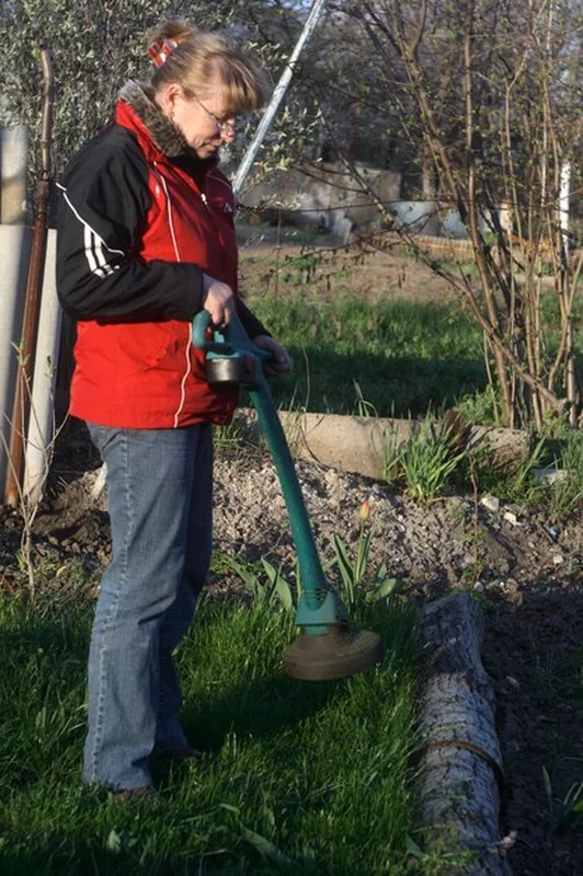 Kobieta używająca sprzętu ogrodniczego, stojąc na podwórku