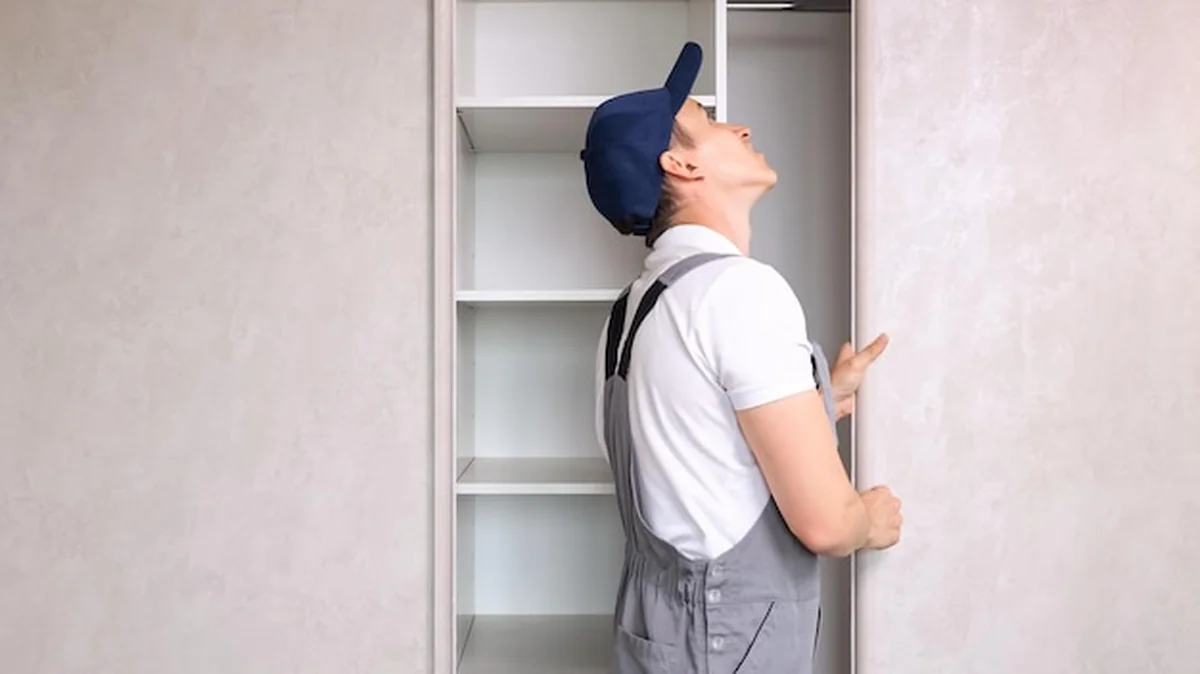 Mechanik w mundurze sprawdza zepsutą szafę w jasnej sypialni