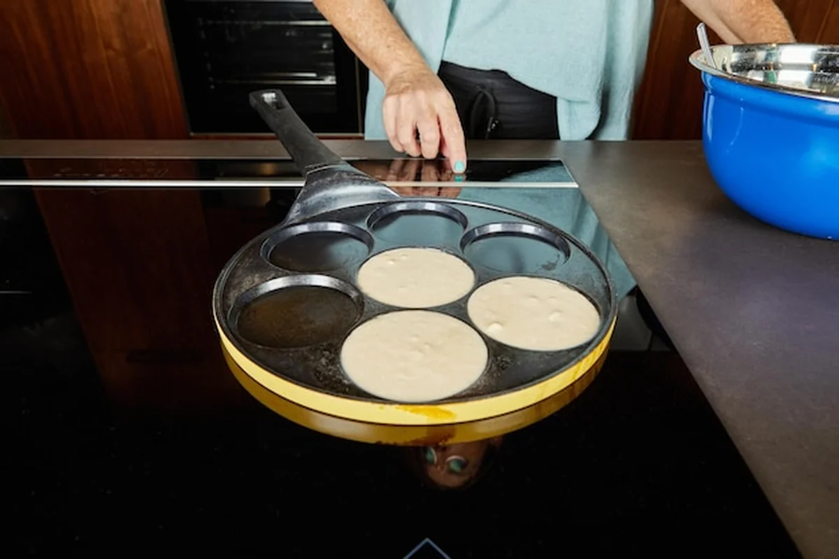 Osoba wlewa ciasto do naleśników na kuchence